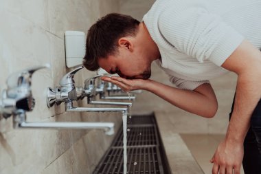 Bir müslüman abdest alıyor. Dua etmeden önce Müslümanların dini temizliği. Namazdan önce vücudu temizleme süreci. 