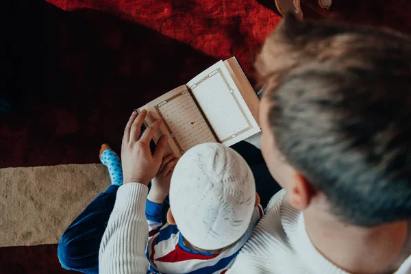 ムスリムの祈りの父と息子をモスクで礼拝し ホリー ブック クルアーンを読む — ストック写真