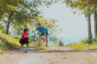 A young couple resting after an exhausting run in the early morning on an idyllic forest road.