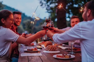 Bir grup mutlu arkadaş tatil tatillerini fıskiyelerle kutlarken ve kırmızı şarap içerken aynı zamanda güzel bir yaz akşamı nehir kenarında piknik yapıyorlar.. 