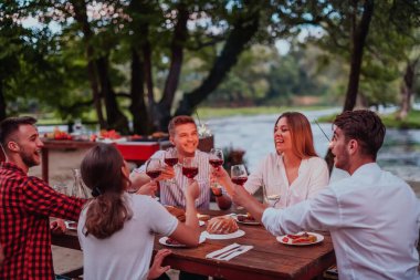 Bir grup mutlu arkadaş tatil tatillerini fıskiyelerle kutlarken ve kırmızı şarap içerken aynı zamanda güzel bir yaz akşamı nehir kenarında piknik yapıyorlar.. 