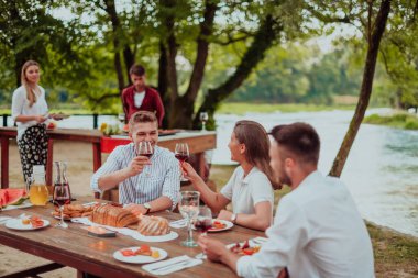 Bir grup mutlu arkadaş yaz tatili boyunca dışarıda piknik yapıyorlar. Nehir kenarında güzel bir doğada.. 