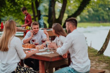 Bir grup mutlu arkadaş yaz tatili boyunca dışarıda piknik yapıyorlar. Nehir kenarında güzel bir doğada.. 