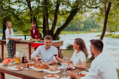 Bir grup mutlu arkadaş yaz tatili boyunca dışarıda piknik yapıyorlar. Nehir kenarında güzel bir doğada.. 