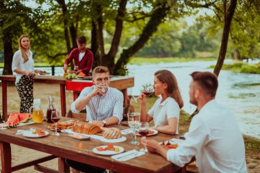 Bir grup mutlu arkadaş yaz tatili boyunca dışarıda piknik yapıyorlar. Nehir kenarında güzel bir doğada.. 