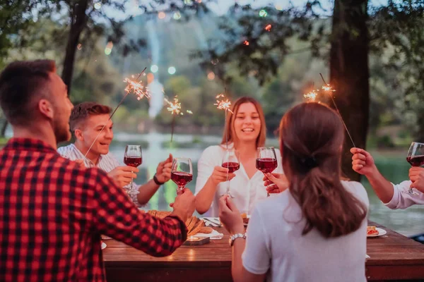 Bir grup mutlu arkadaş tatil tatillerini fıskiyelerle kutlarken ve kırmızı şarap içerken aynı zamanda güzel bir yaz akşamı nehir kenarında piknik yapıyorlar.. 