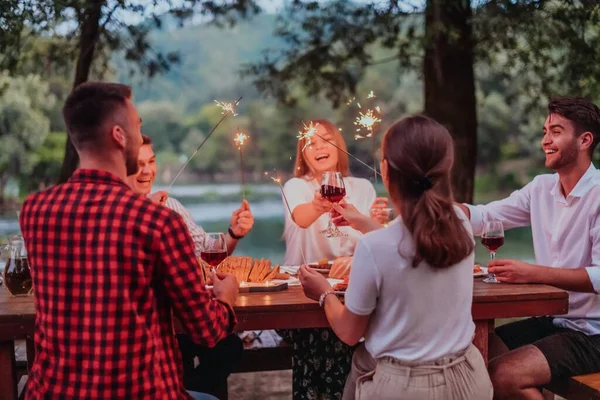 Bir grup mutlu arkadaş tatil tatillerini fıskiyelerle kutlarken ve kırmızı şarap içerken aynı zamanda güzel bir yaz akşamı nehir kenarında piknik yapıyorlar.. 