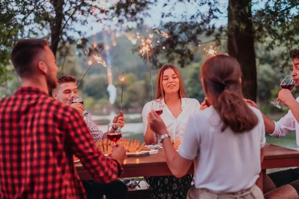 Bir grup mutlu arkadaş tatil tatillerini fıskiyelerle kutlarken ve kırmızı şarap içerken aynı zamanda güzel bir yaz akşamı nehir kenarında piknik yapıyorlar.. 