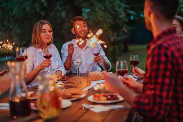 Bir grup mutlu arkadaş tatil tatillerini fıskiyelerle kutlarken ve kırmızı şarap içerken aynı zamanda güzel bir yaz akşamı nehir kenarında piknik yapıyorlar.. 