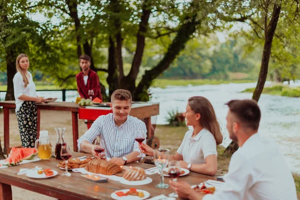 Bir grup mutlu arkadaş yaz tatili boyunca dışarıda piknik yapıyorlar. Nehir kenarında güzel bir doğada.. 