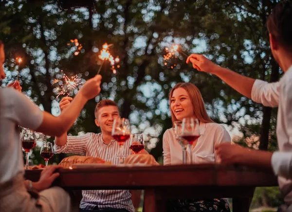 Bir grup mutlu arkadaş tatil tatillerini fıskiyelerle kutlarken ve kırmızı şarap içerken aynı zamanda güzel bir yaz akşamı nehir kenarında piknik yapıyorlar.. 