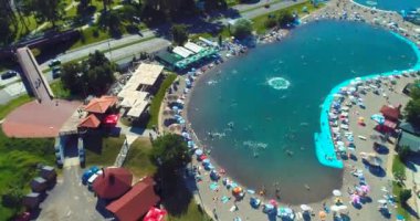 Aerial drone view of overcrowded urban lake during peak of tourist season. Crowd of people swimming in the sea at summer. Large group of people in swimsuit bathing in ocean during vacation. High
