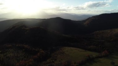 Cinematic Aerial flight over the hill with forest and tree tops with a beautiful sunset in the background. High quality 4k footage