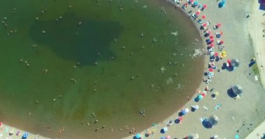 Aerial drone view of overcrowded urban lake during peak of tourist season. Crowd of people swimming in the sea at summer. Large group of people in swimsuit bathing in ocean during vacation. High