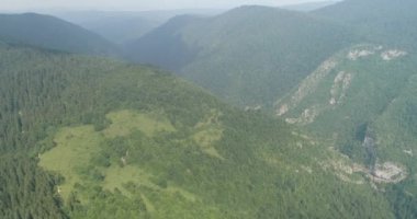 Aerial Cinematic clip: Drone flying over a beautiful summer landscape of endless meadows and hills. Top view to the farm wheatfield. High quality 4k footage