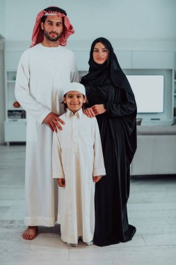portrait of young happy arabian muslim family couple with son in traditional clothes spending time together during the month of Ramadan at home. High quality photo