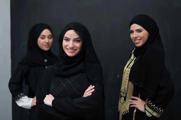 黒の背景に隔離されたヒジャーブとファッショナブルなドレスで美しいイスラム教徒の女性のグループの肖像画 ストック画像