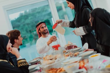 Muslim family having Iftar dinner drinking water to break feast. Eating traditional food during Ramadan feasting month at home. The Islamic Halal Eating and Drinking in modern home.