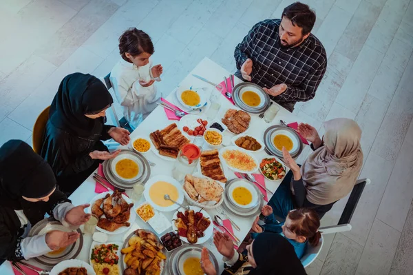 Top view of Muslim family having Iftar dinner drinking water to break feast. Eating traditional food during Ramadan feasting month at home. The Islamic Halal Eating and Drinking in modern home.