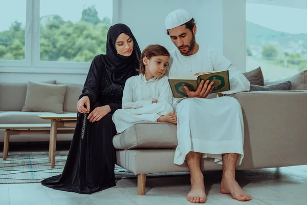 Happy Muslim family enjoying the holy month of Ramadan while praying and reading the Quran together in a modern home.