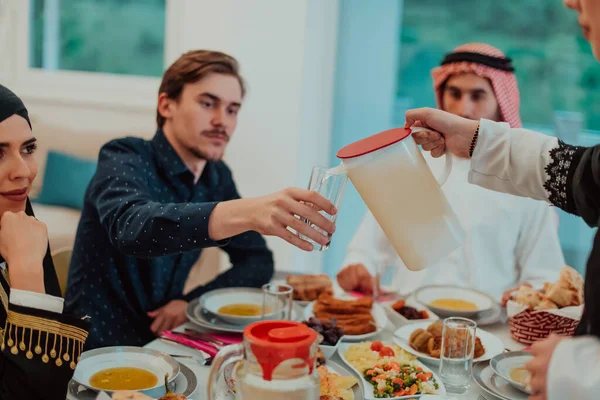 イフタールのディナー飲料水を持っているイスラム教徒の家族はごちそうを破る ラマダーン月の家で伝統的な食べ物を食べる 現代の家庭でのイスラム教のハラル食と飲料 — ストック写真