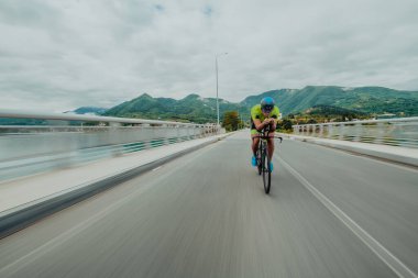 Full length portrait of an active triathlete in sportswear and with a protective helmet riding a bicycle. Selective focus . 