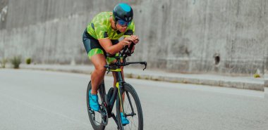 Full length portrait of an active triathlete in sportswear and with a protective helmet riding a bicycle. Selective focus . 