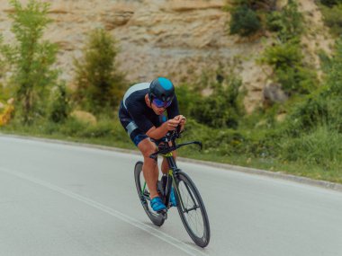Full length portrait of an active triathlete in sportswear and with a protective helmet riding a bicycle. Selective focus . 