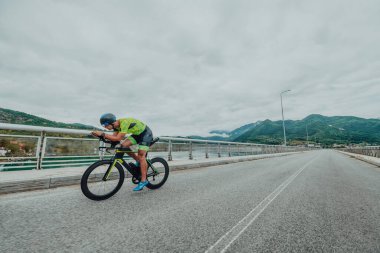 Full length portrait of an active triathlete in sportswear and with a protective helmet riding a bicycle. Selective focus . 