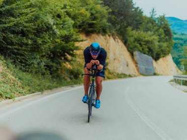 Full length portrait of an active triathlete in sportswear and with a protective helmet riding a bicycle. Selective focus . 