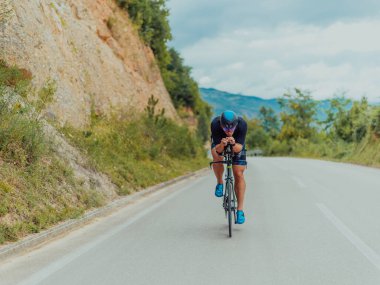 Full length portrait of an active triathlete in sportswear and with a protective helmet riding a bicycle. Selective focus . 
