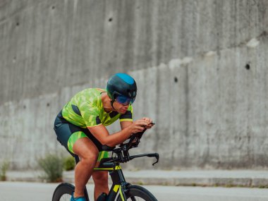Full length portrait of an active triathlete in sportswear and with a protective helmet riding a bicycle. Selective focus . 