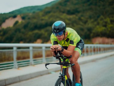 Full length portrait of an active triathlete in sportswear and with a protective helmet riding a bicycle. Selective focus . 