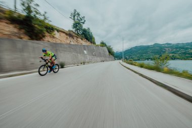 Full length portrait of an active triathlete in sportswear and with a protective helmet riding a bicycle. Selective focus . 