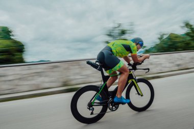 Full length portrait of an active triathlete in sportswear and with a protective helmet riding a bicycle. Selective focus . 