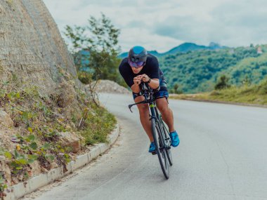 Full length portrait of an active triathlete in sportswear and with a protective helmet riding a bicycle. Selective focus . 