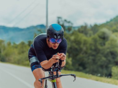 Full length portrait of an active triathlete in sportswear and with a protective helmet riding a bicycle. Selective focus . 