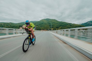 Full length portrait of an active triathlete in sportswear and with a protective helmet riding a bicycle. Selective focus . 