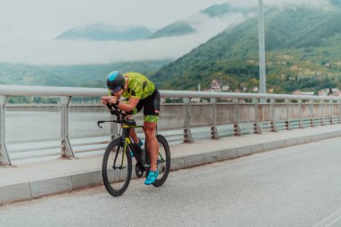 Full length portrait of an active triathlete in sportswear and with a protective helmet riding a bicycle. Selective focus . 