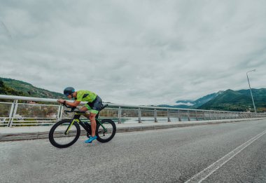 Full length portrait of an active triathlete in sportswear and with a protective helmet riding a bicycle. Selective focus . 