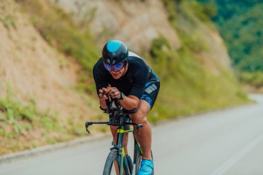 Full length portrait of an active triathlete in sportswear and with a protective helmet riding a bicycle. Selective focus . 