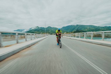Full length portrait of an active triathlete in sportswear and with a protective helmet riding a bicycle. Selective focus . 