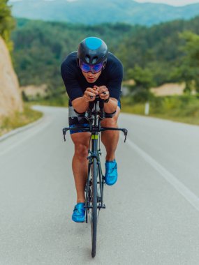 Full length portrait of an active triathlete in sportswear and with a protective helmet riding a bicycle. Selective focus . 