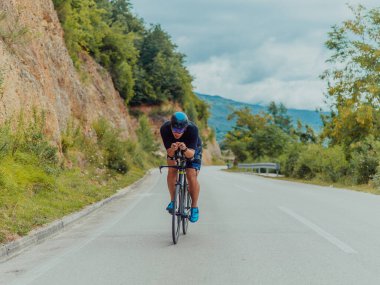 Full length portrait of an active triathlete in sportswear and with a protective helmet riding a bicycle. Selective focus . 