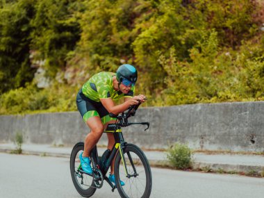 Full length portrait of an active triathlete in sportswear and with a protective helmet riding a bicycle. Selective focus . 