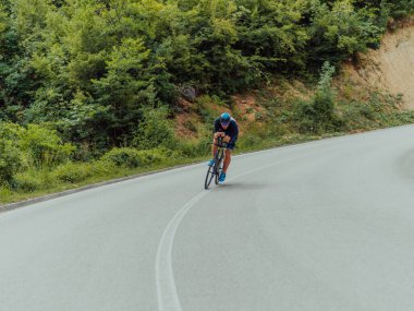 Full length portrait of an active triathlete in sportswear and with a protective helmet riding a bicycle. Selective focus . 