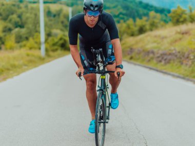 Full length portrait of an active triathlete in sportswear and with a protective helmet riding a bicycle. Selective focus . 