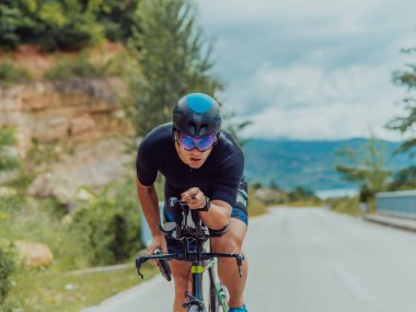 Full length portrait of an active triathlete in sportswear and with a protective helmet riding a bicycle. Selective focus . 