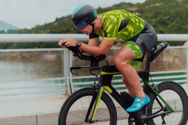 Full length portrait of an active triathlete in sportswear and with a protective helmet riding a bicycle. Selective focus . 