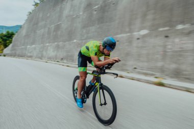 Full length portrait of an active triathlete in sportswear and with a protective helmet riding a bicycle. Selective focus . 